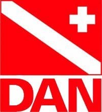 Diver-Alert-Network_redimensionné Logo carré rouge comportant une bande blanche en diagonale représentant un plongeur, une petite croix blanche dans le coin supérieur droit et les lettres « DAN » en rouge et en gras en dessous.